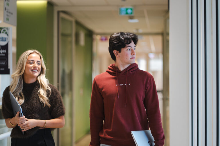 twee associate degree studenten lopen door de gang van het schoolgebouw in Roosendaal