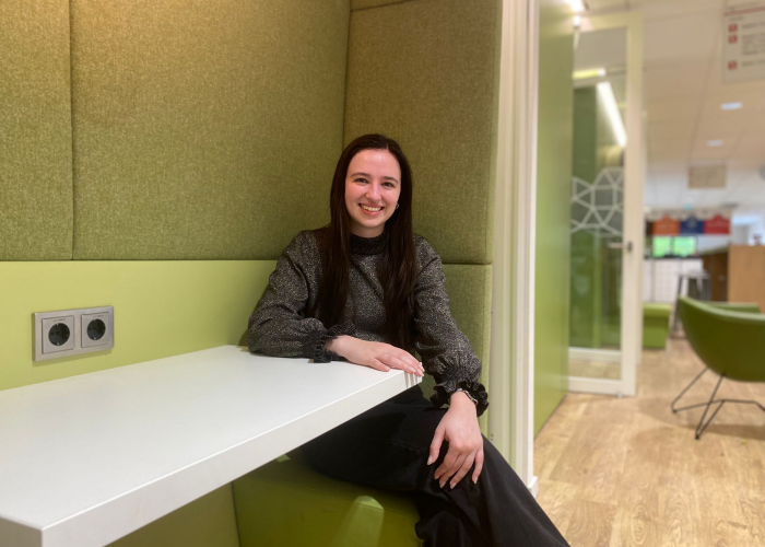 Student Danique Vrolijk van de Associate degree Human Resource Management draagt een glittertop en poseert binnen op een bankje