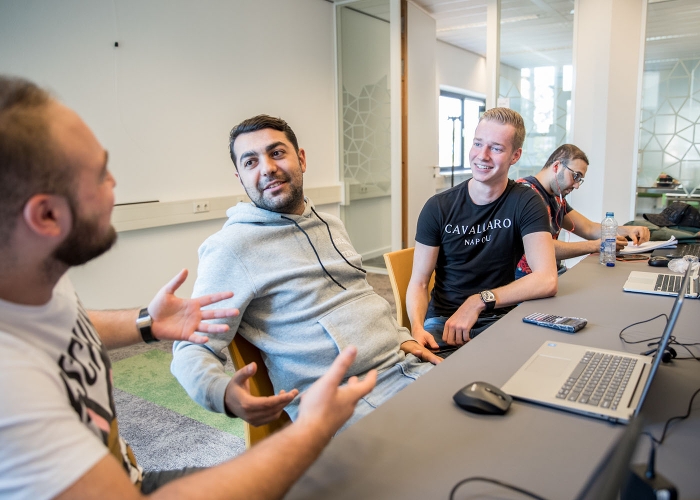 4 studenten overleggen aan een tafel bij de Associate degrees Academie