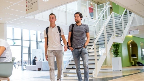 2 studenten lopen door het gebouw van de Associate degrees Academie